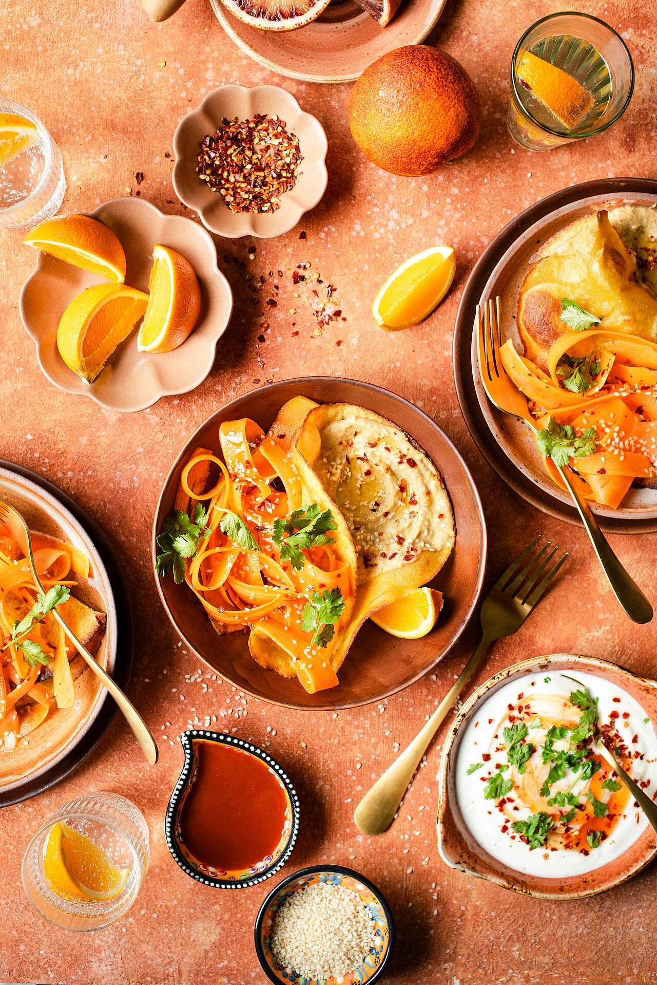 A table with plates of food and bowls of hummus