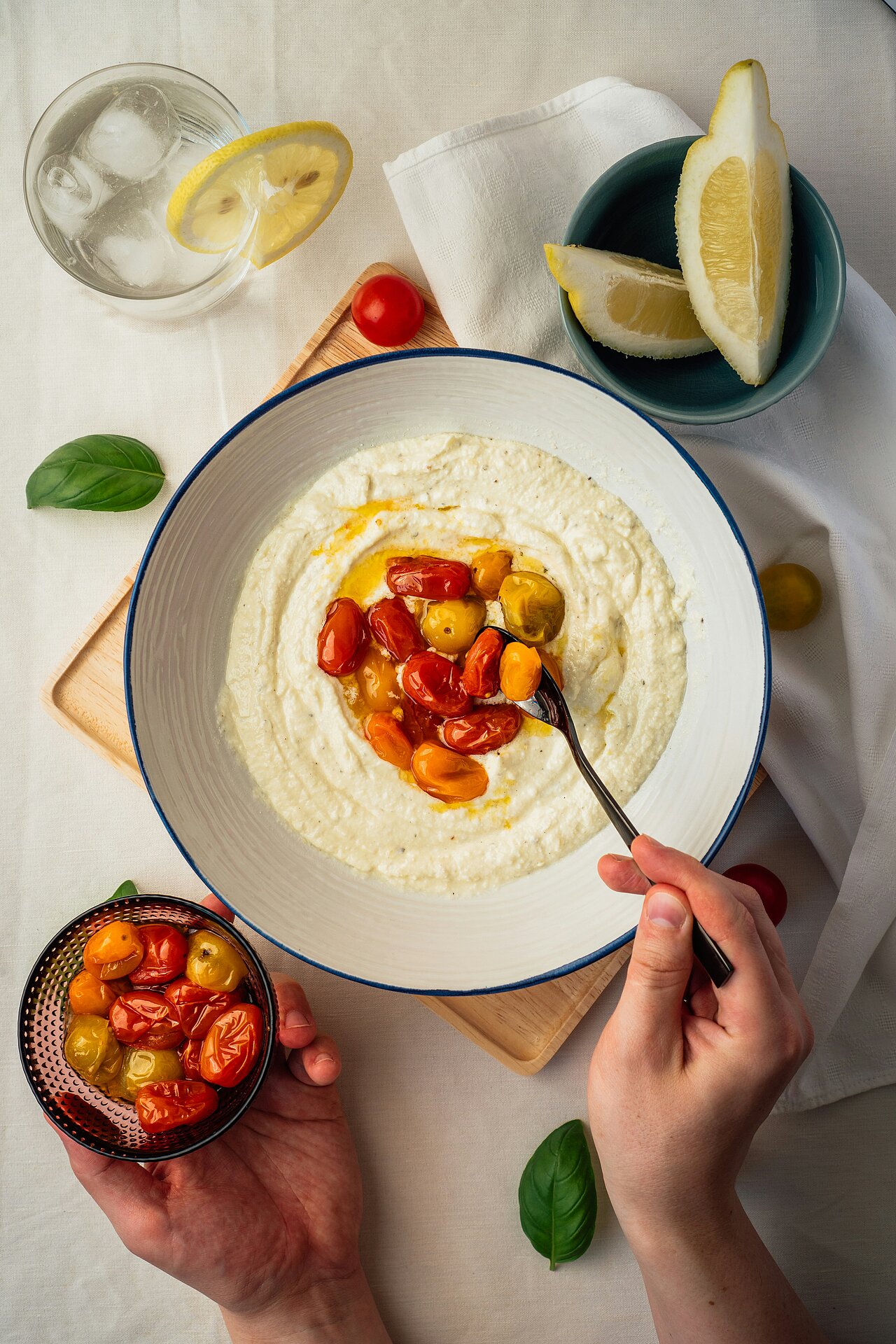 A person is holding a fork in a bowl of hummus