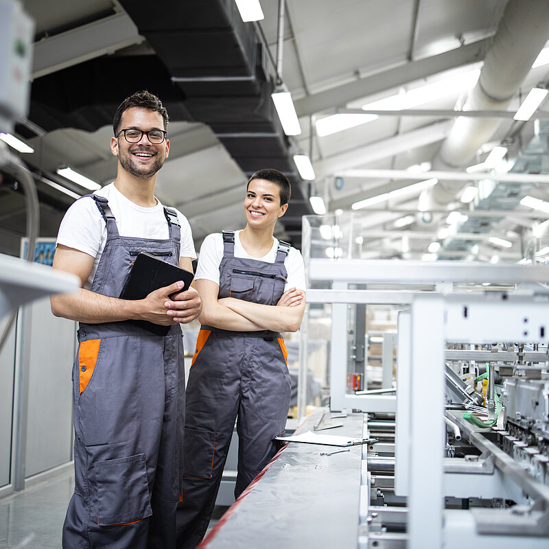 Produktionslinienarbeitern, die eine Verpackungsindustriemaschine in der Druckerei steuern.