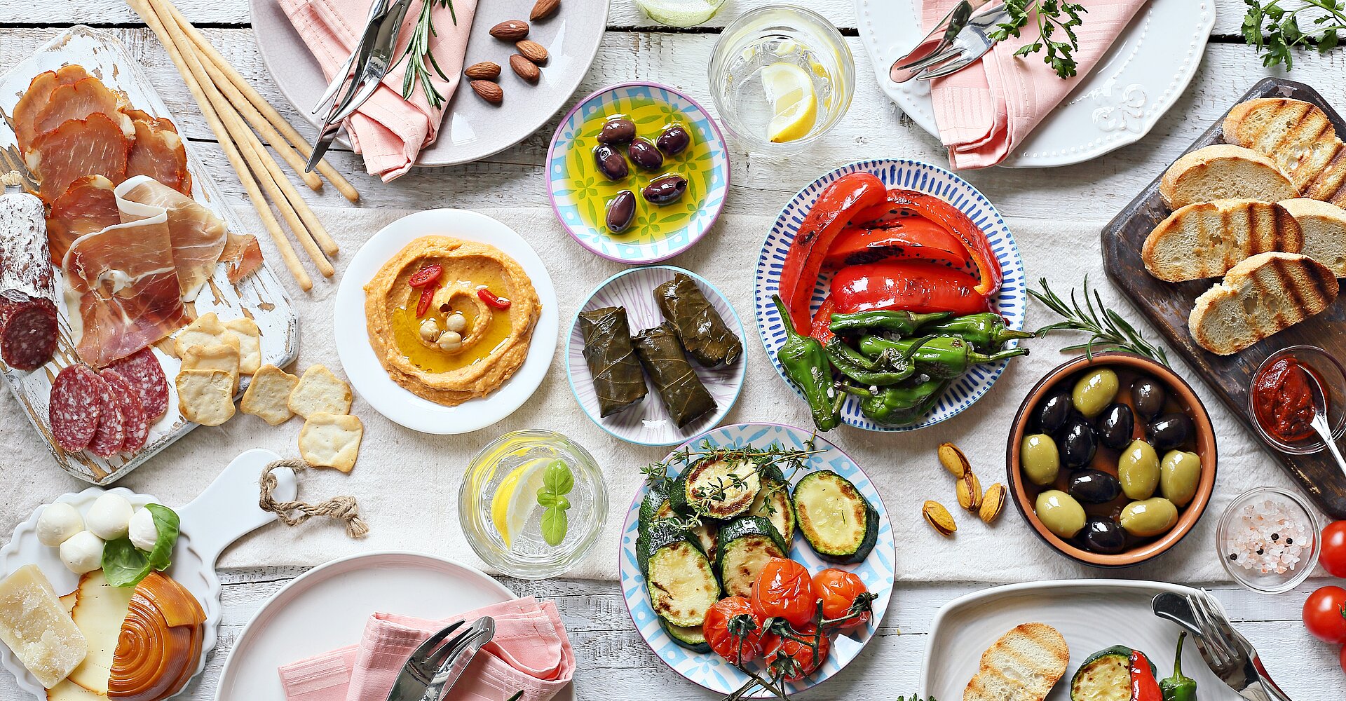 Mediterrane Vorspeisen Tischkonzept. Diner Tisch mit Antipasti Auswahl: gegrilltes Gemüse,  Wurstwaren, Fleisch und Wurstwaren, Schinken, Oliven, Käse, Hummus und geröstetem Brot.
