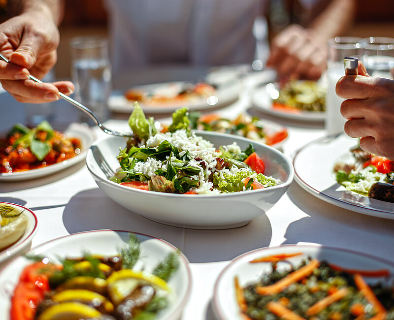 Paar beim Mittagessen mit frischen Salaten und Vorspeisen