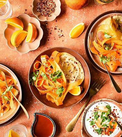 Ein Tisch mit Tellern mit Essen und Schüsseln mit Soßen 
