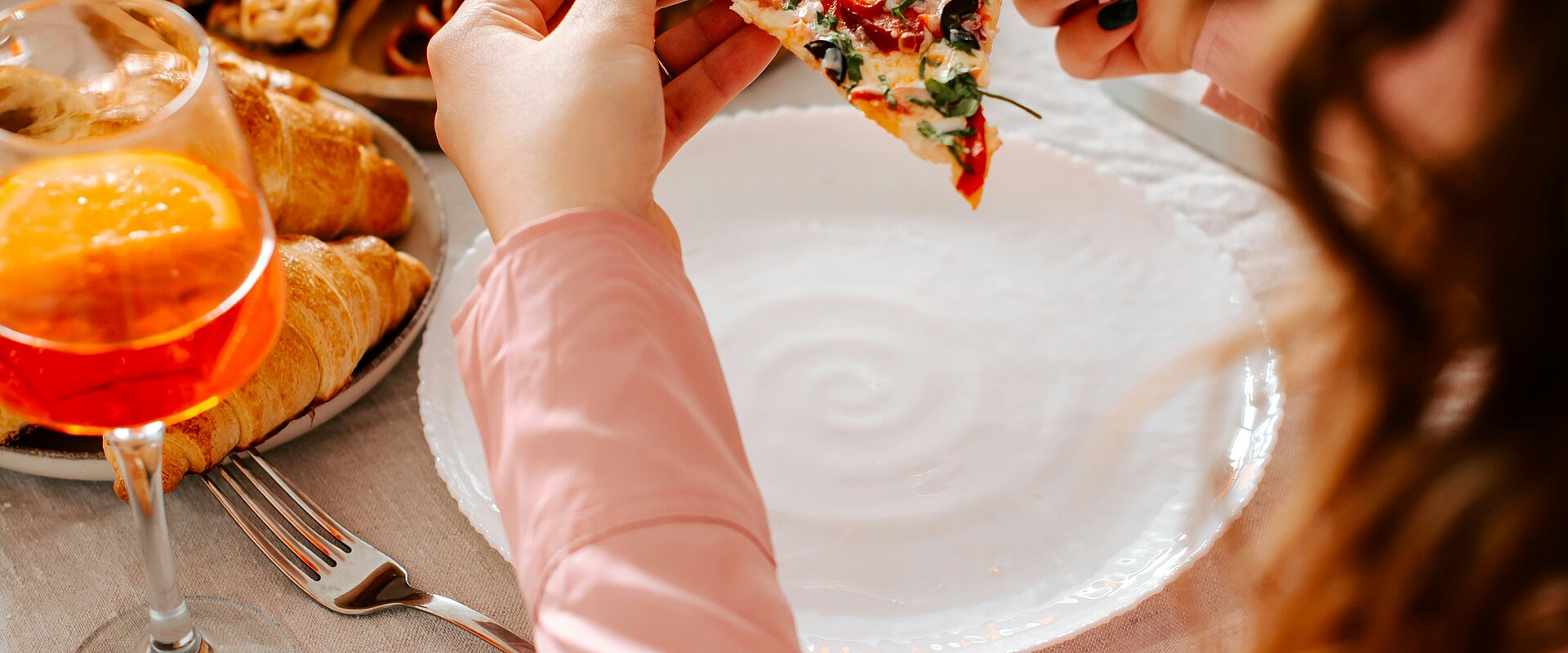 Eine Frau isst ein Stück Pizza an einem Tisch