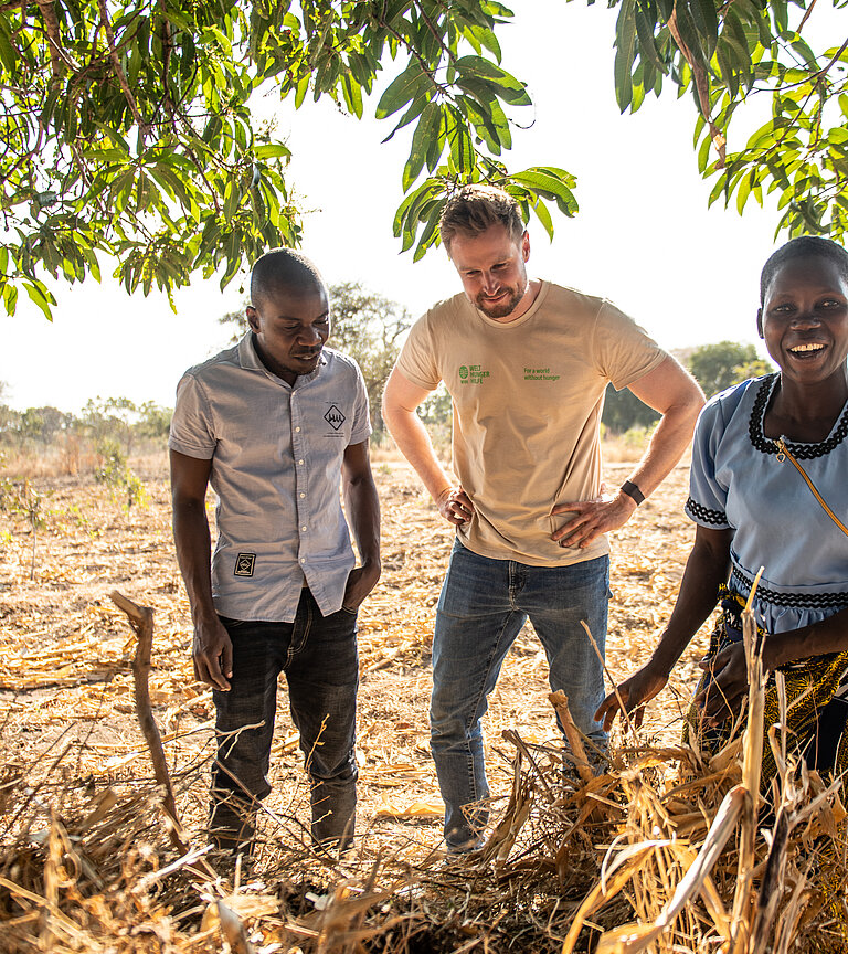 Two locals show a Welthungerhilfe member how to work in the fields.