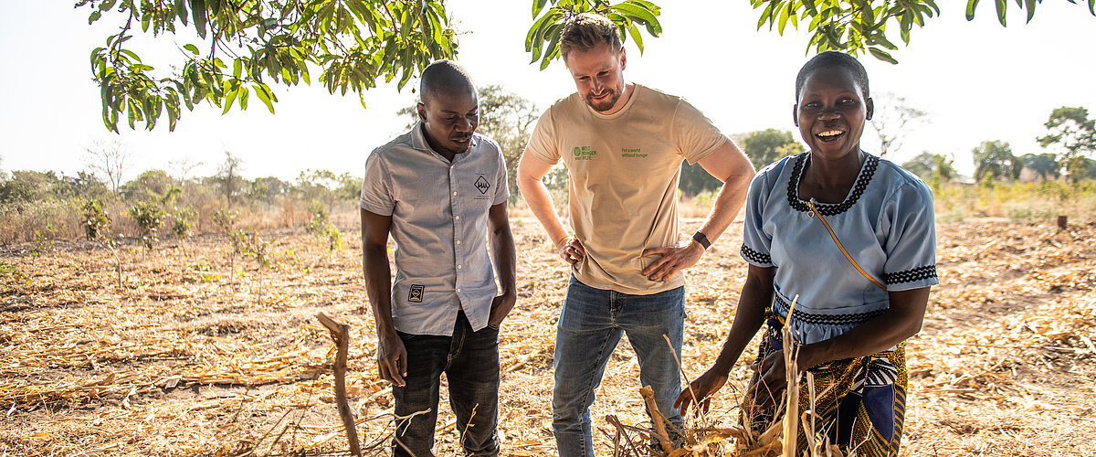 Two locals show a Welthungerhilfe member how to work in the fields.