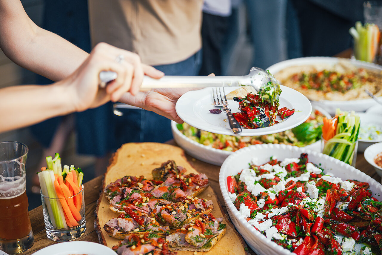 Frauenhand gibt eine Mahlzeit auf einen Teller mit Mittagessen