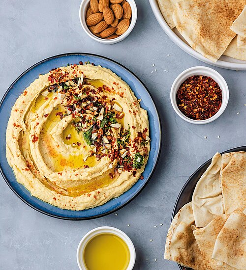 Ein Teller mit Hummus, Faldenbrot und eine Schüssel Olivenöl 