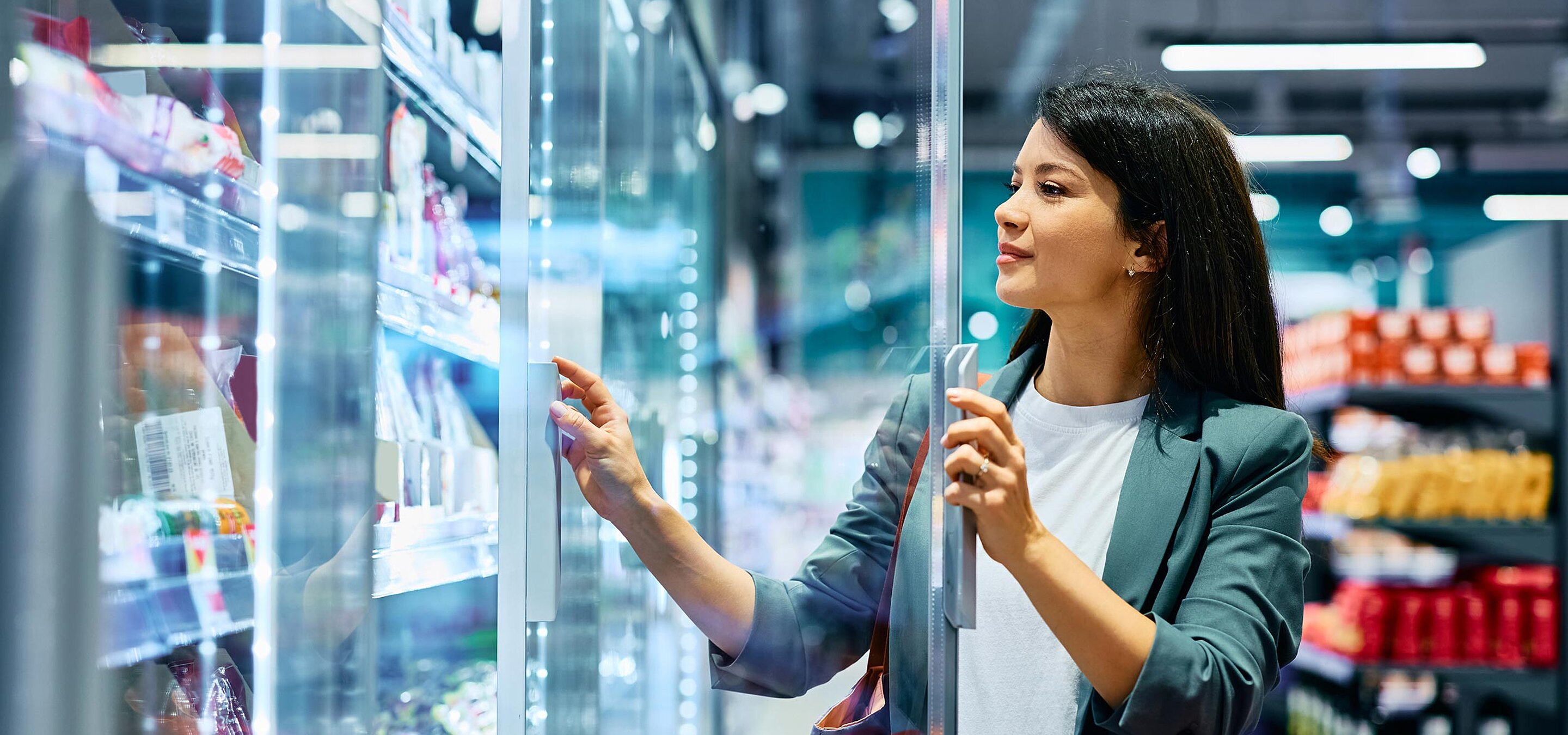 Lächelnde Frau, die Lebensmittel in der Kühlabteilung eines Supermarkts kauft.