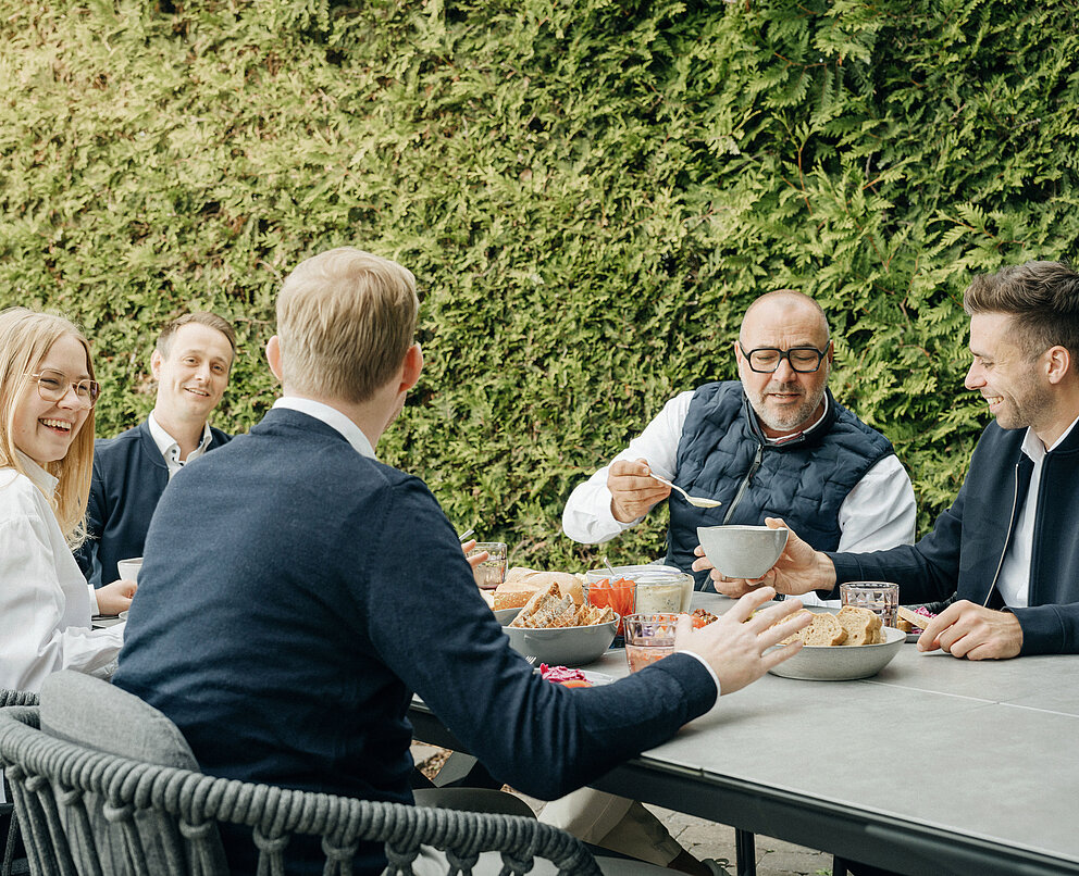 A group of employees is sitting together and tasting Kühlmann products.