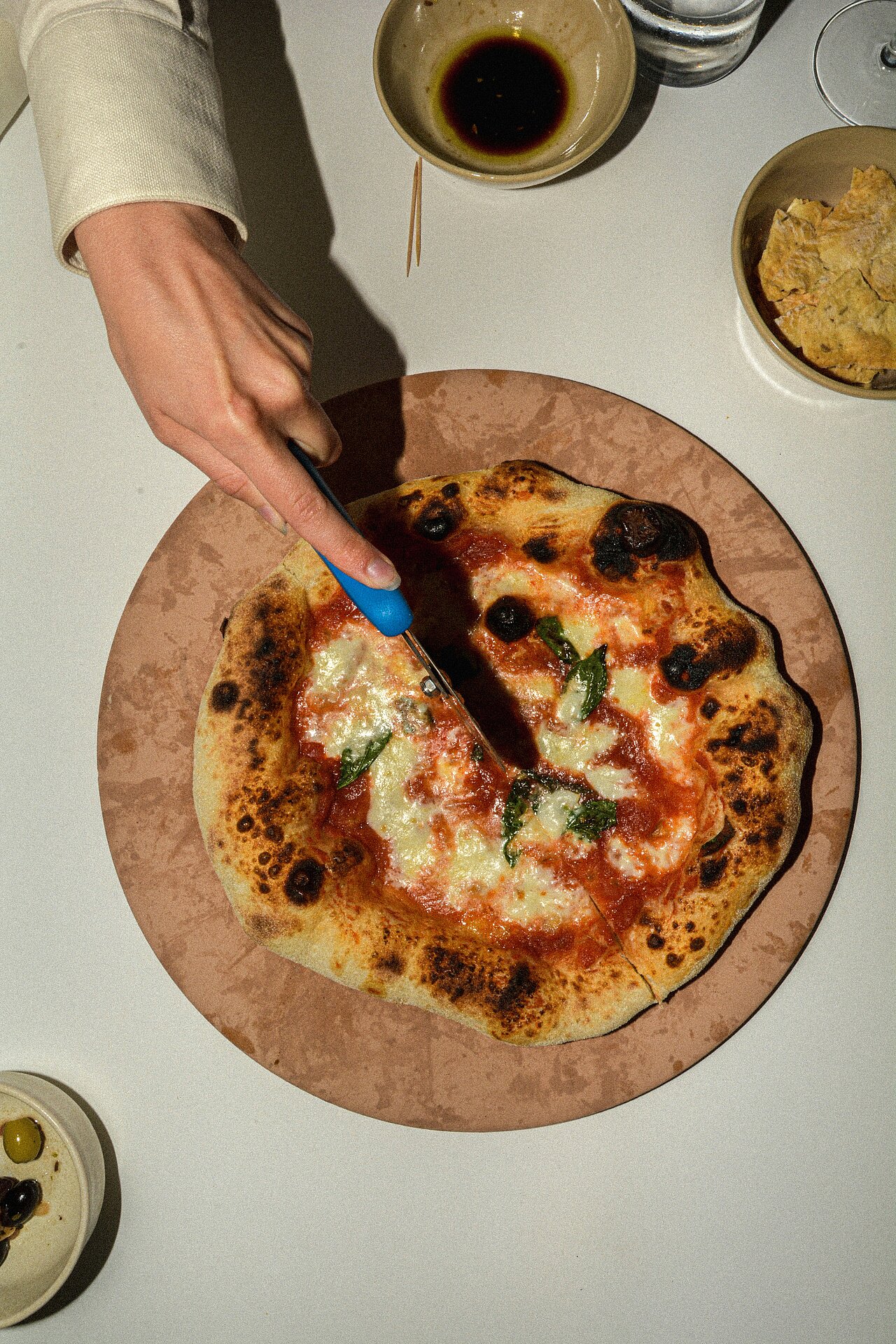 a person who cuts a pizza with a knife