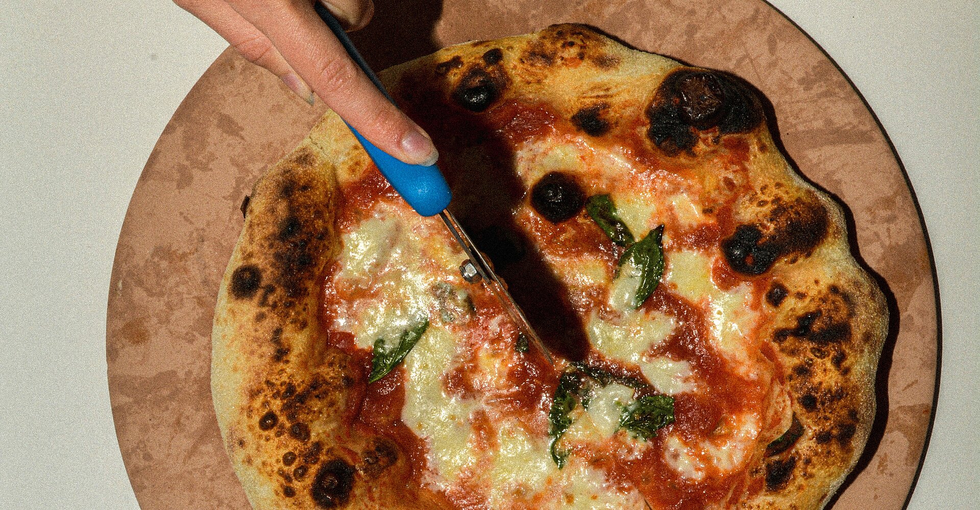 eine Person, die eine Pizza mit einem Messer schneidet