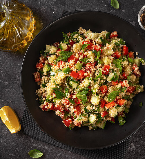 Ein Teller mit vegan erfrischendem Couscous-Salat auf dem Rücken