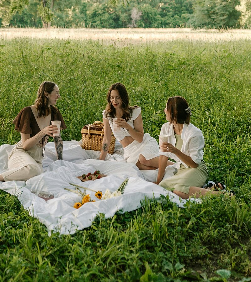 Eine Gruppe von Frauen, die auf einer üppigen grünen Wiese sitzen