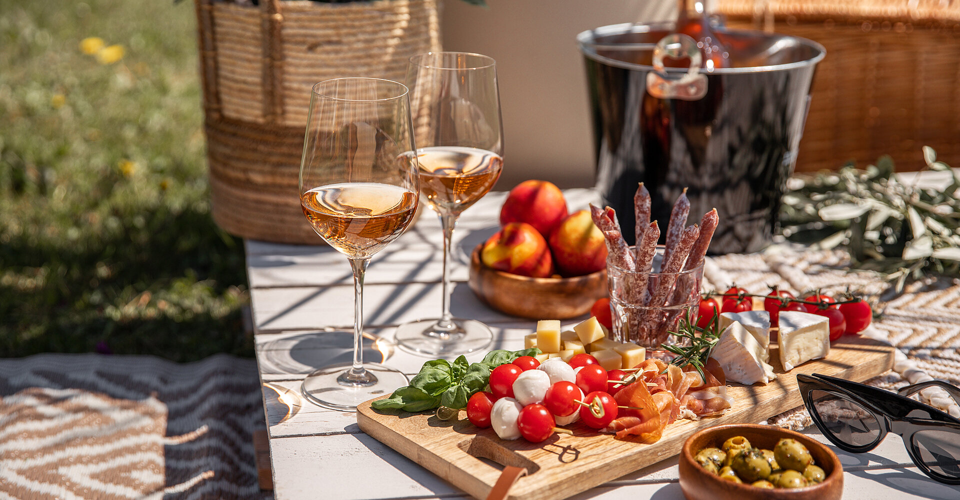 Roséweingläser mit Antipasti Picknick-Snacks auf sonnigem Gartenpartytisch